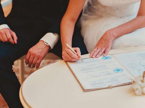 жениъ и невеста подписывают документ