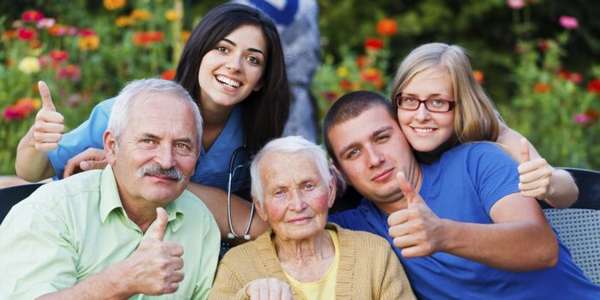 пожилые женщина и мужчина и взрослые дети фотографируются с выставленным большим пальцем