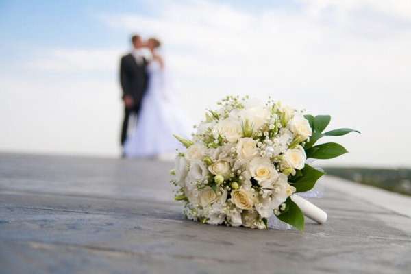 свадебный букет и жених с невестой на фоне