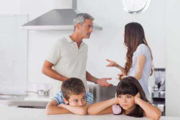 мальчик и девочка за столом на кухне, ссора родителей на фоне
