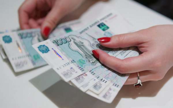 российские деньги в руках с ногтями, покрытыми красным лаком