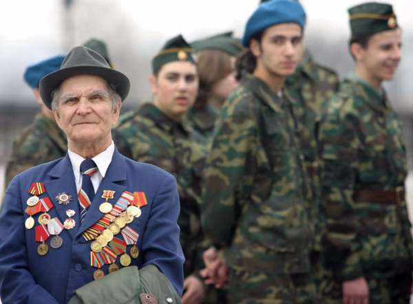 ветеран войны в медалях и солдаты на фоне