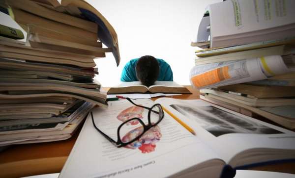 стопки книг и журналов с ручкой и очками на столе