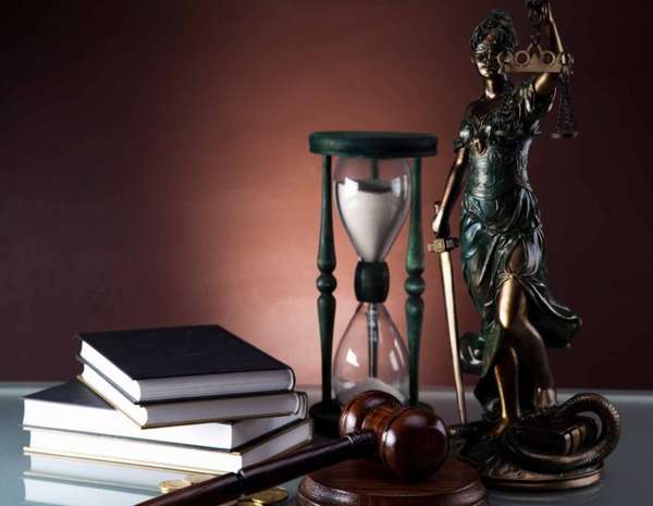 статуя правосудия, книги, песочные часы и судейский молоток на столе